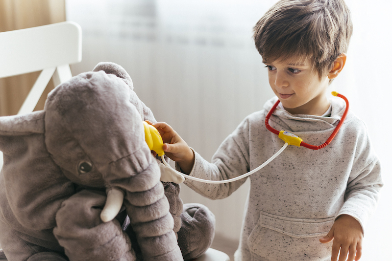 a preschool boy engaged in role play activity playing doctor exploring his interests - supporting entrepreneurial spirit