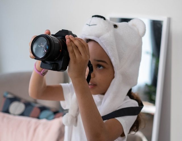 preschool Afro American girl holding a camera exploring her passion and interests through experiential learning 